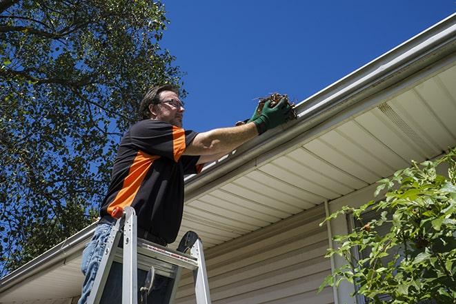 a person replacing a worn-out gutter on a building in Andover